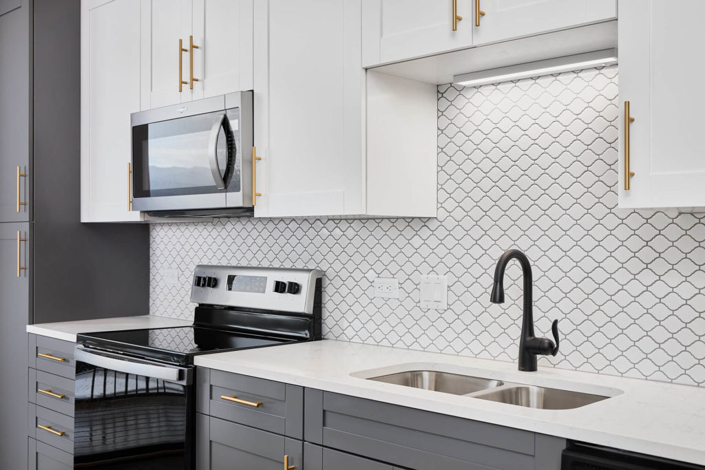 Kitchen with white and grey cabinets with gold handles