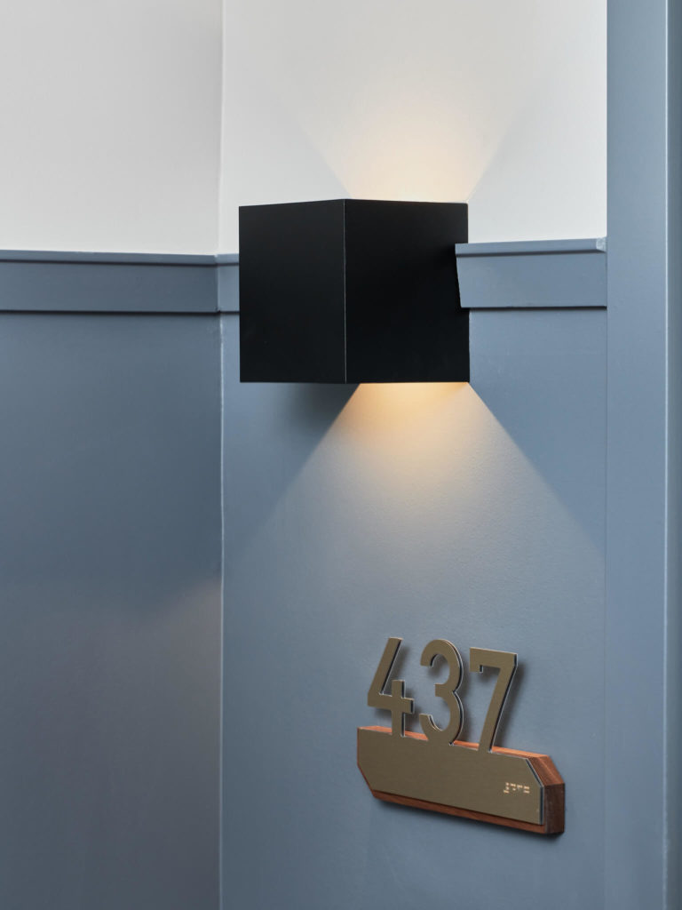 Apartment door with black wall light and number plate